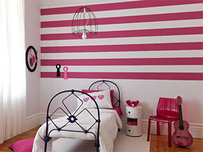 white and pink striped feature wall with white and black furniture pink chair guitar and pillows